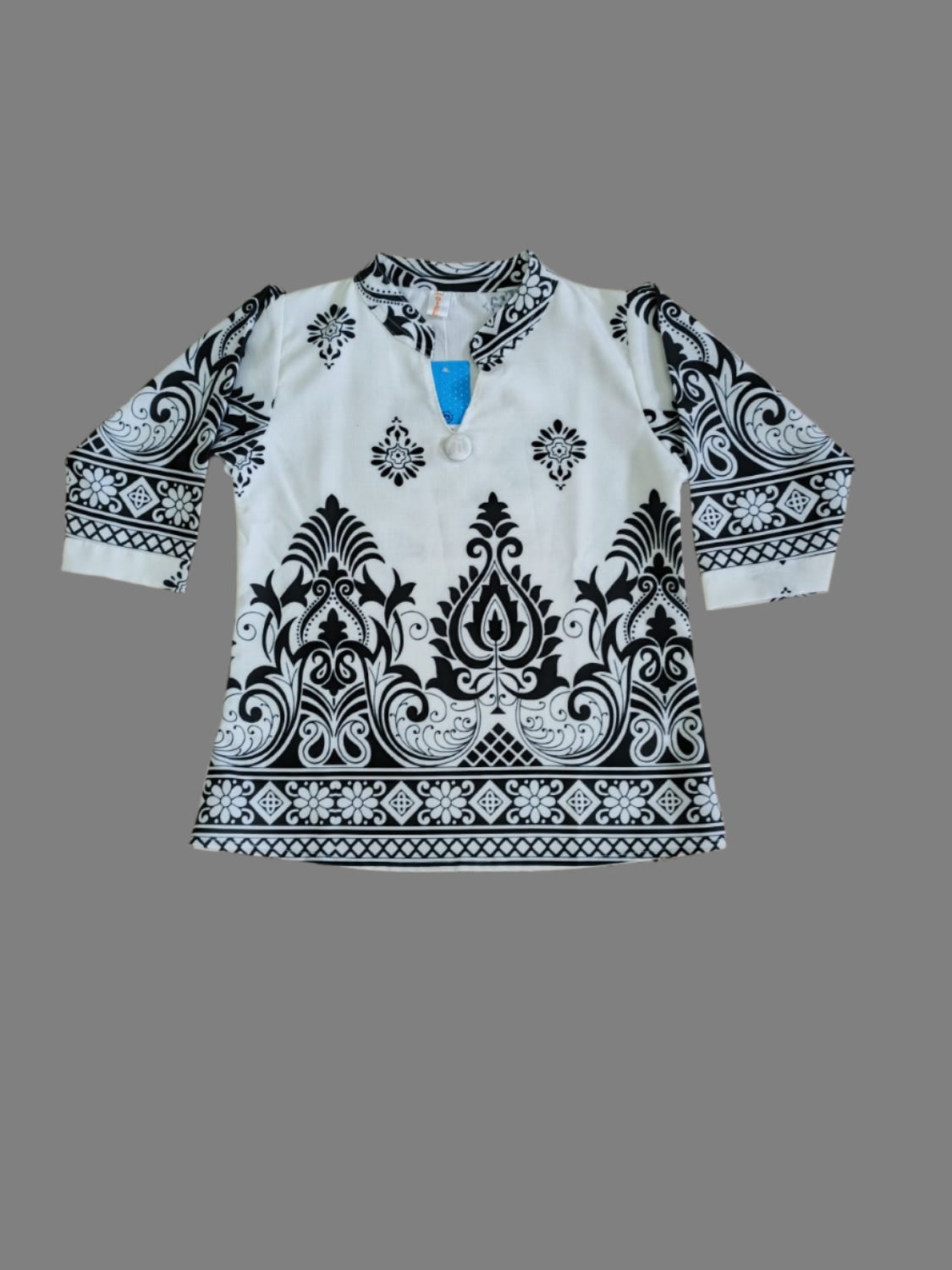 White shirt with black and white pattern on a beige tiled floor