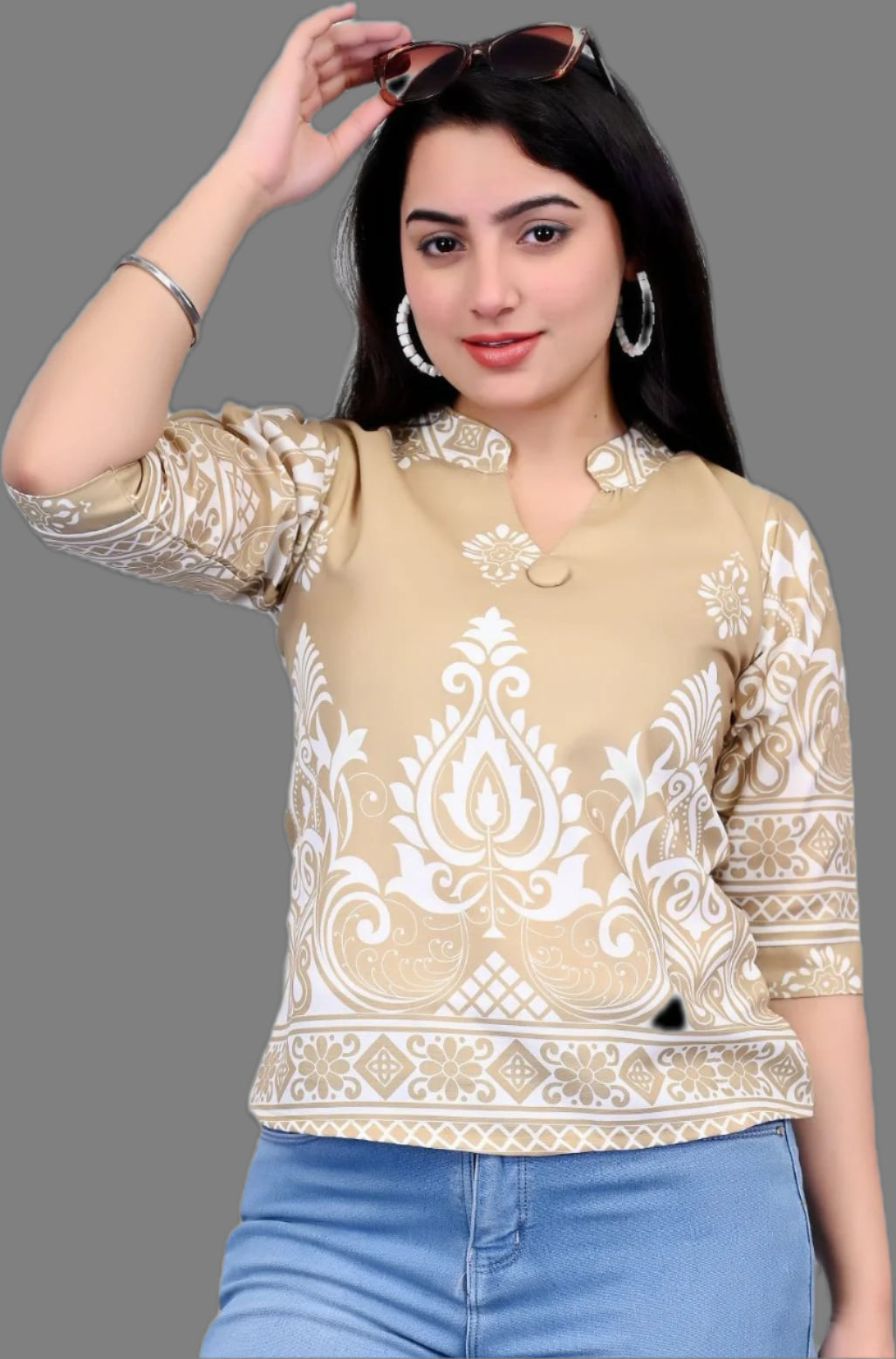 Woman wearing a beige top with white embroidery and blue jeans on a black background